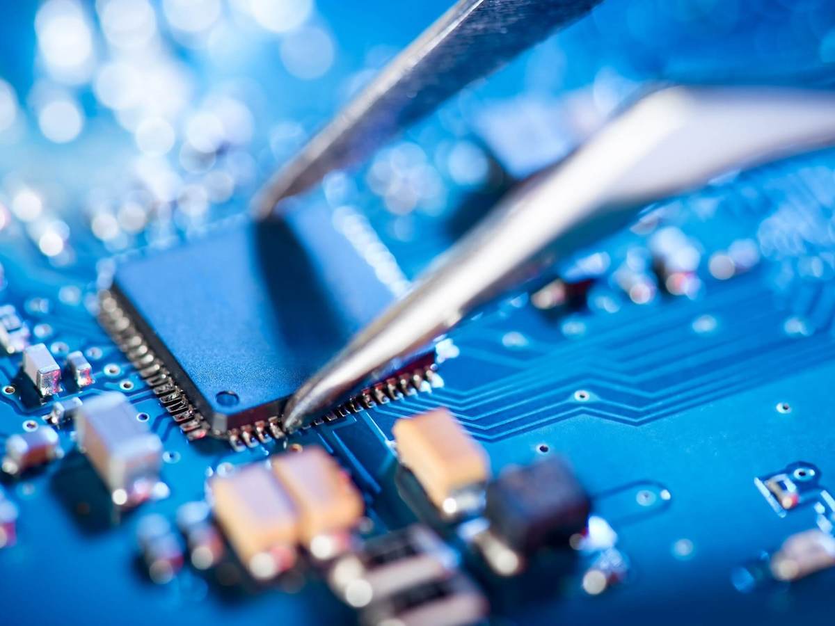 A pair of specialized tweezers places a circuit on a board