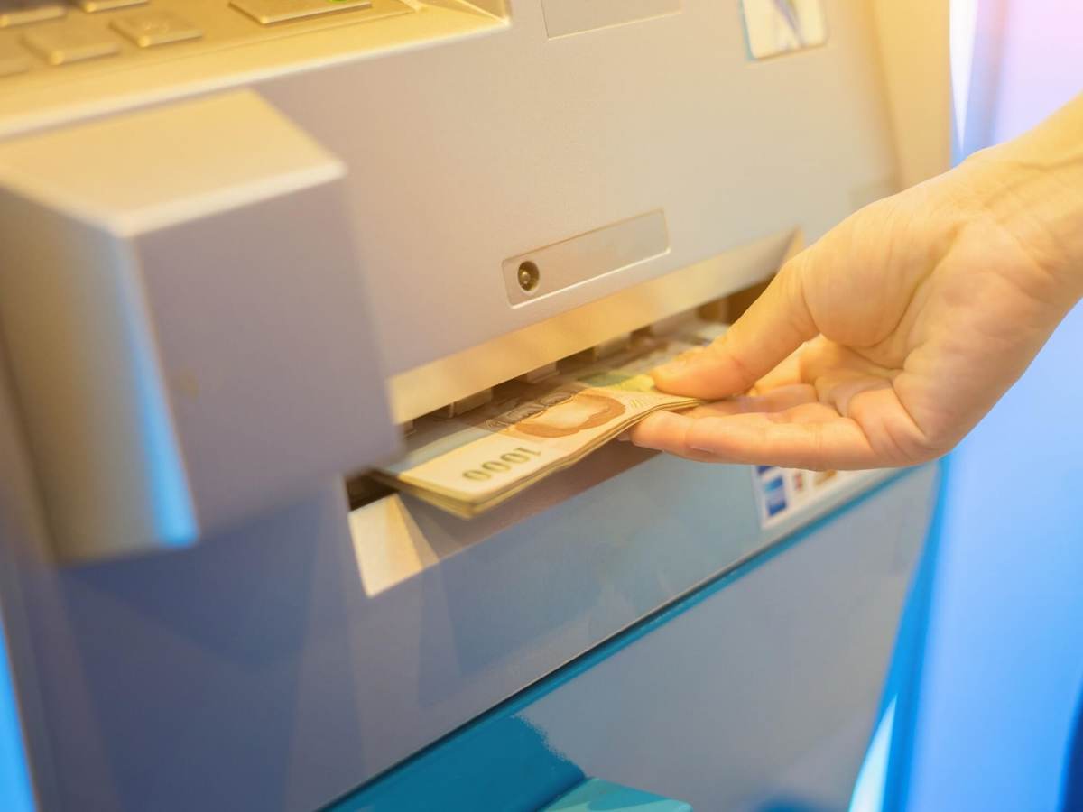 Hand accepts money dispensed from ATM machine