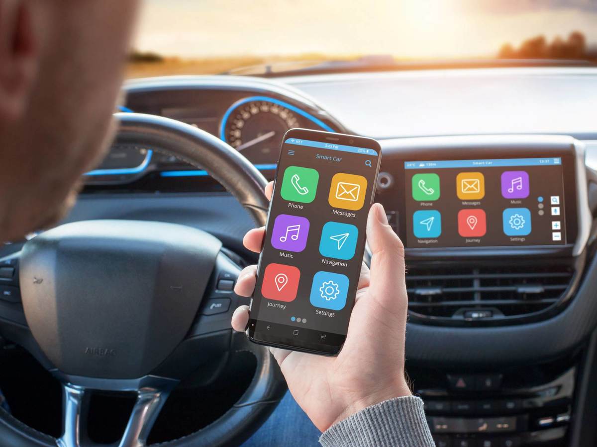 Driver uses a mobile phone with smart driving assistance apps. The app is connected to a car computer and is displayed on the board display.