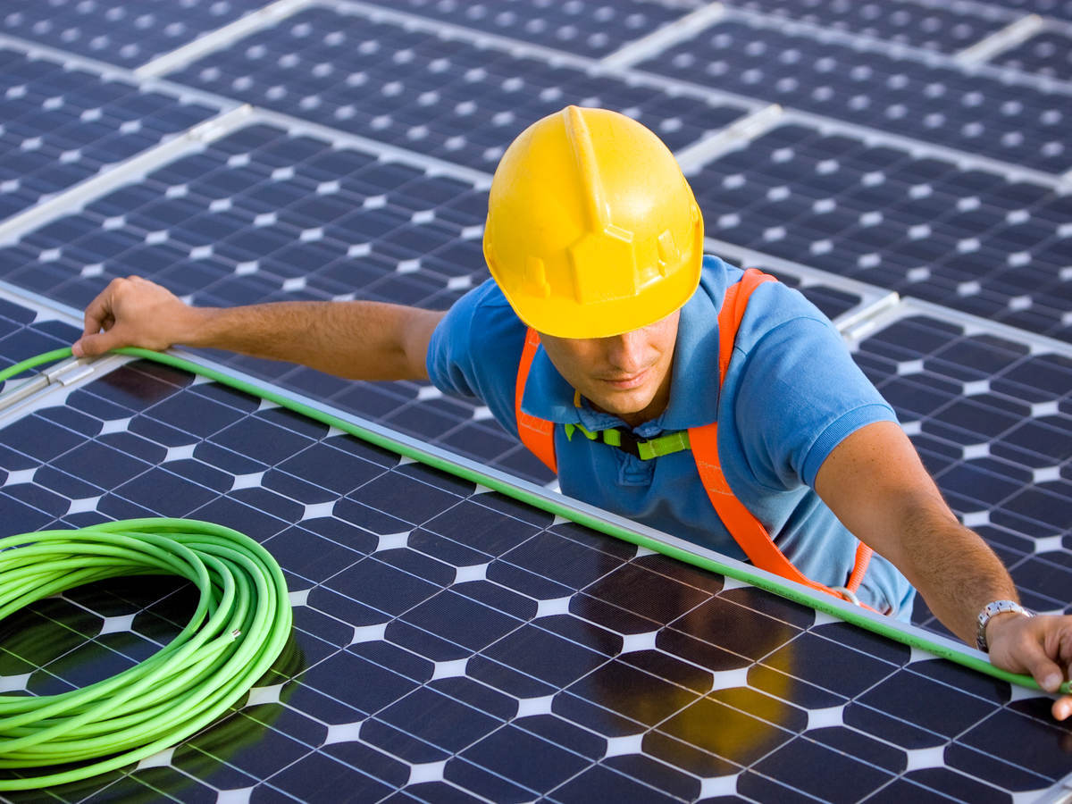 man in hard hat doing wiring on a solar energy panel for wire and cable testing and certification