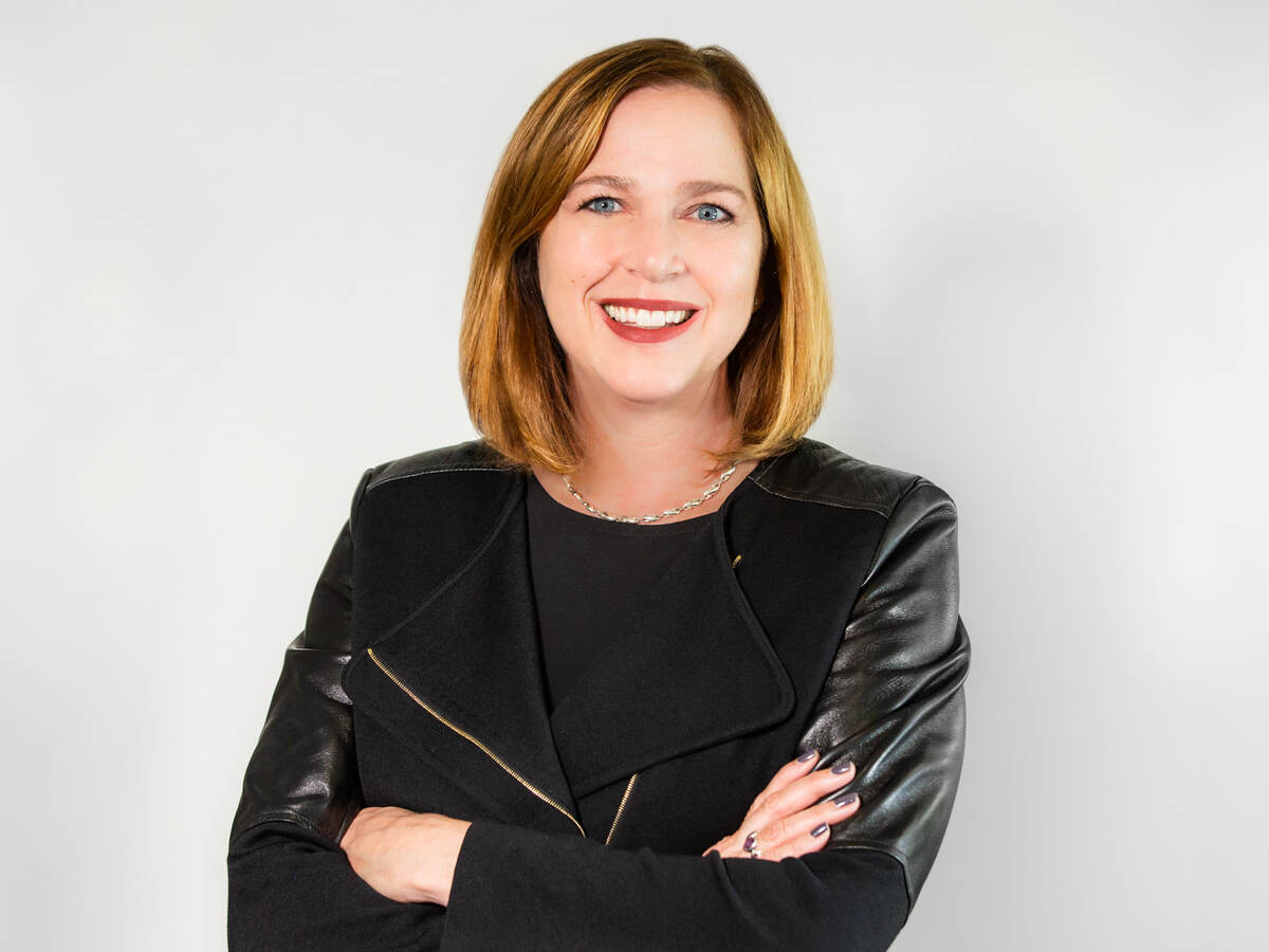 Jen Scanlon, CEO of UL, poses in front of a grey background wearing a black jacket and black dress