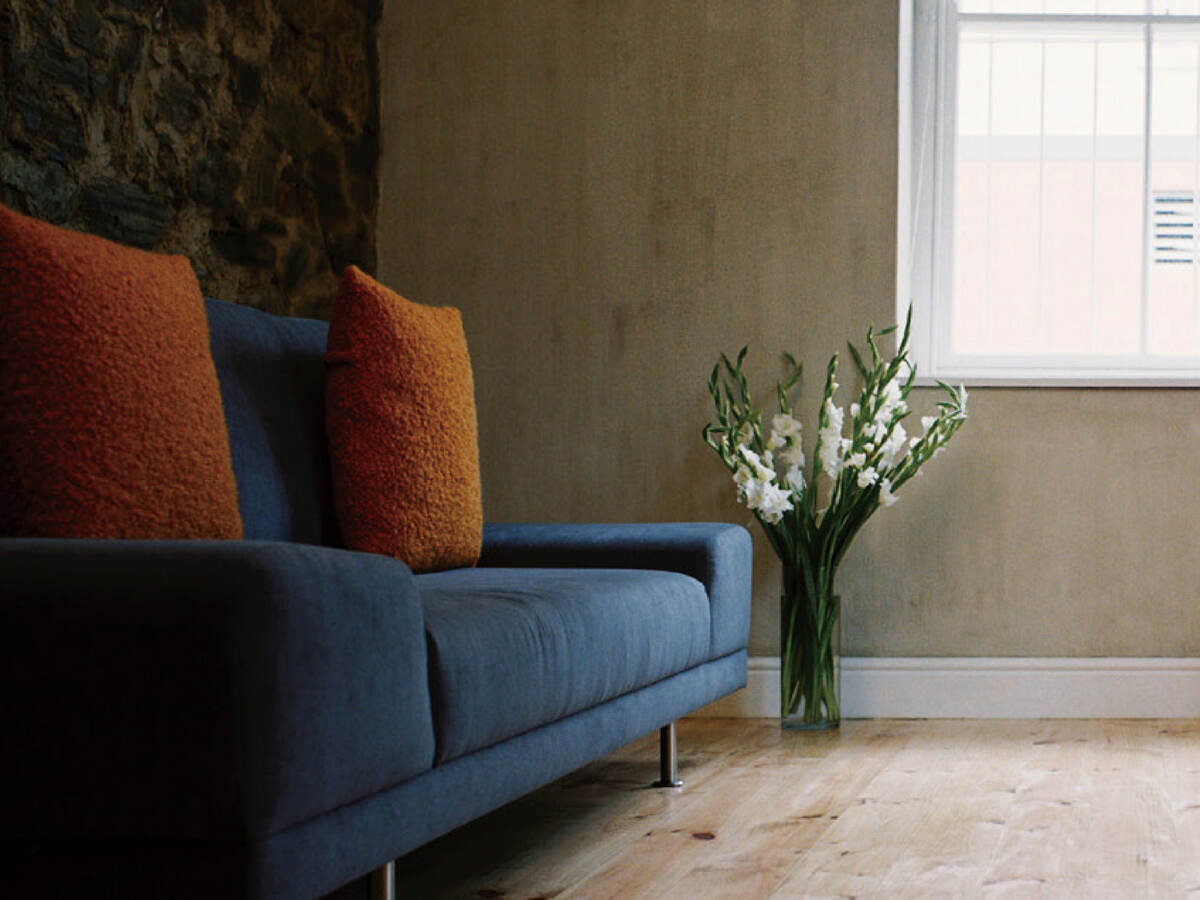 Photo of a blue couch with orange throw pillows