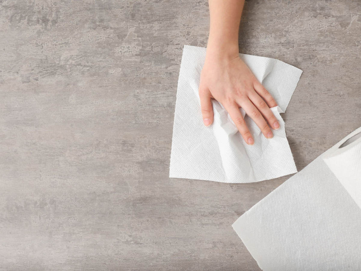 Woman wipes counter with a white paper towel. 