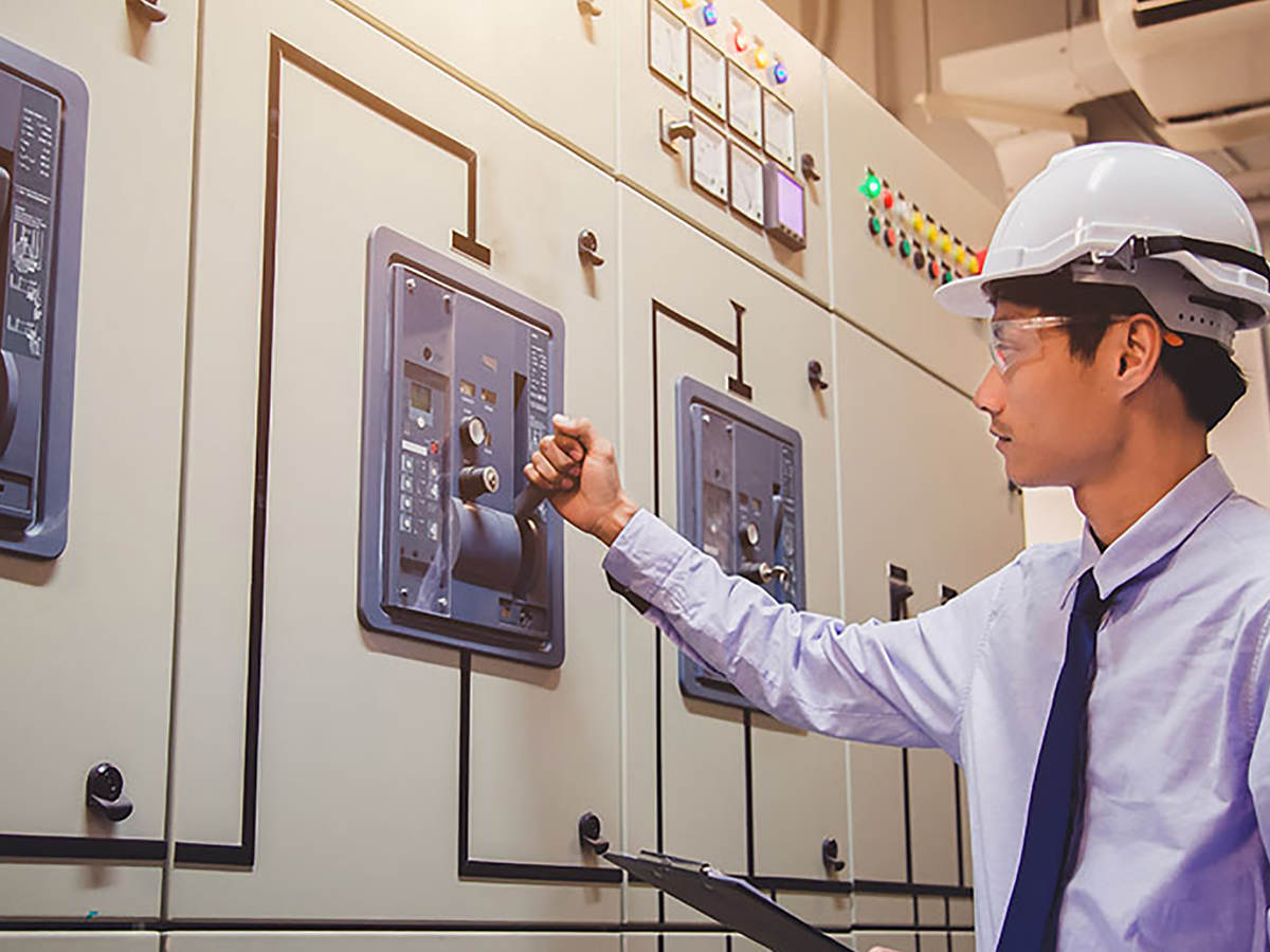 An engineer is checking voltage or current by voltmeter in control panel of power plant