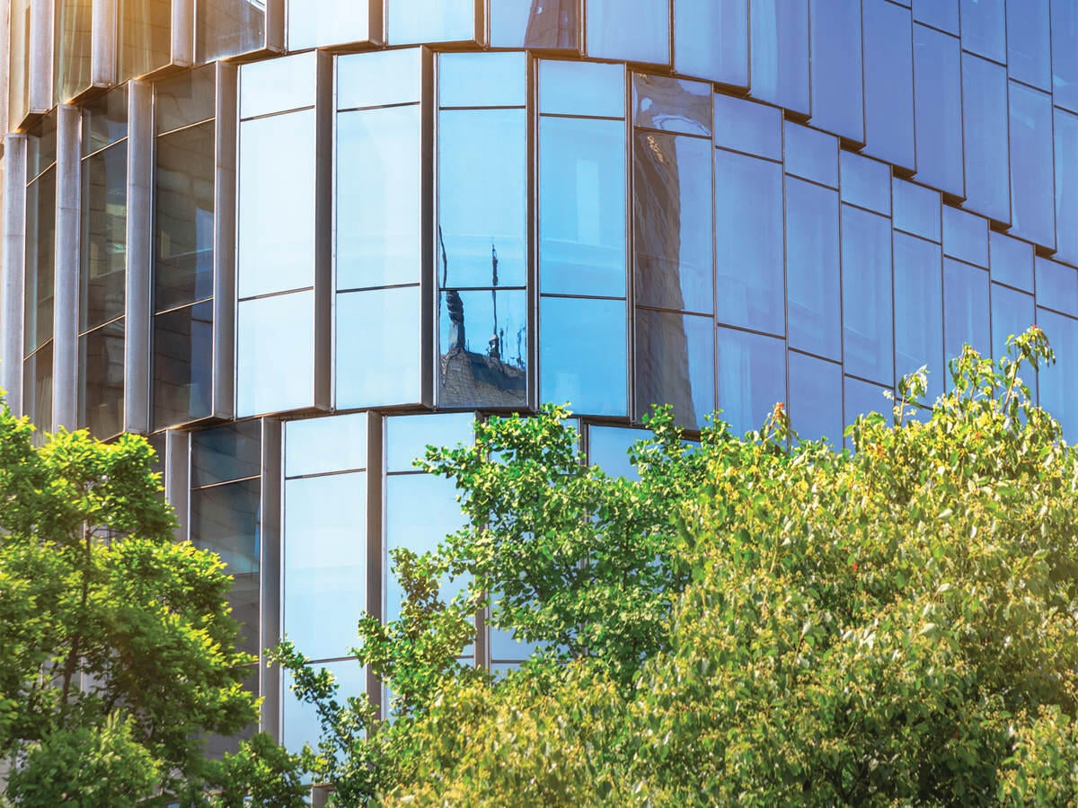 Photo of a blue glass office building with trees in foreground