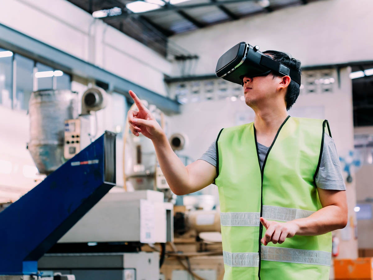 Manufacturing engineer wearing VR goggle headset in virtual reality simulation 