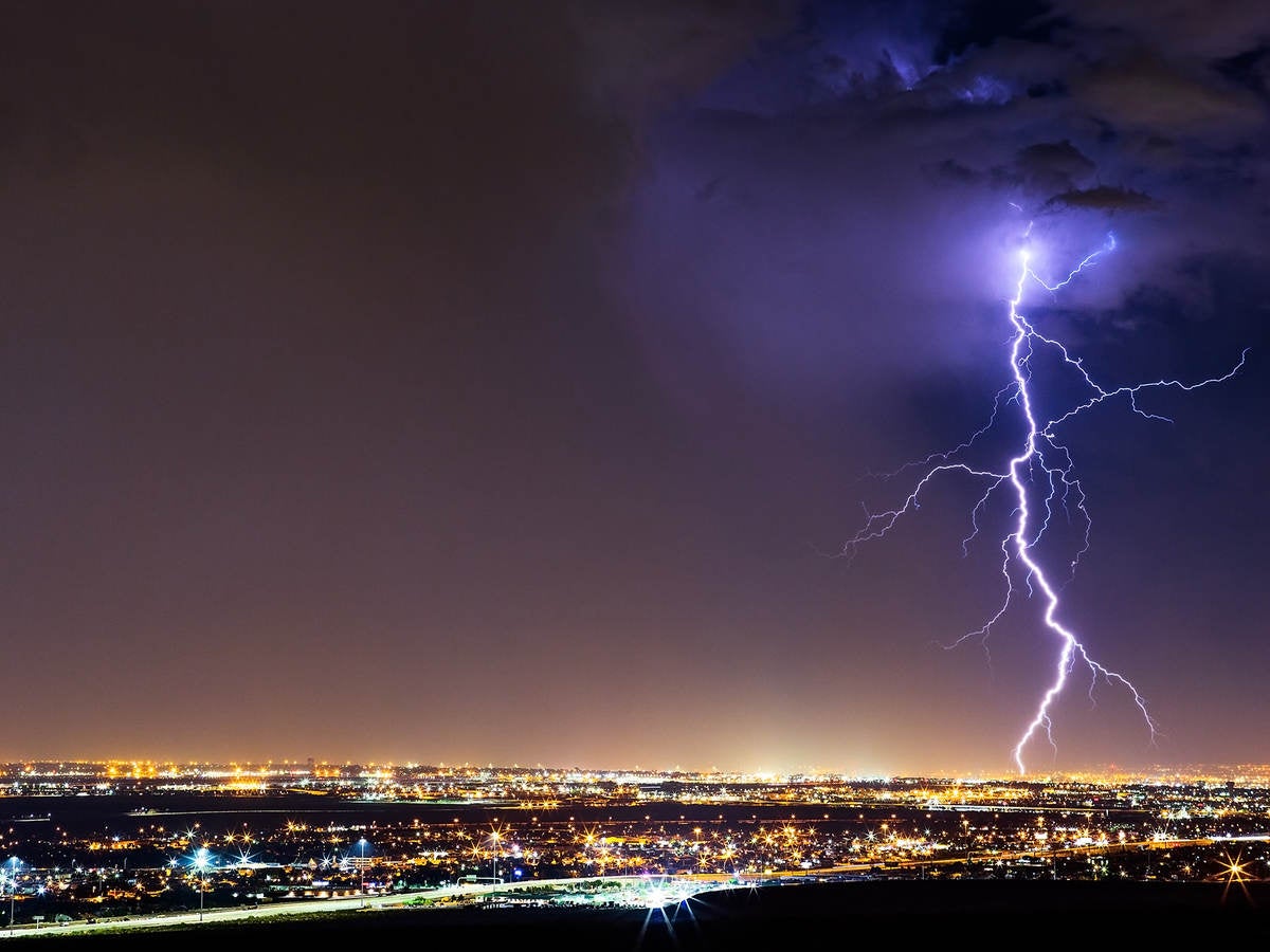 lightning striking cityscape at night 