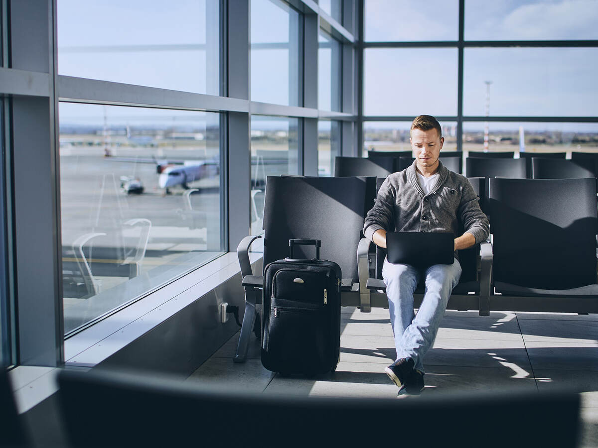 Traveler using laptop in airport terminal
