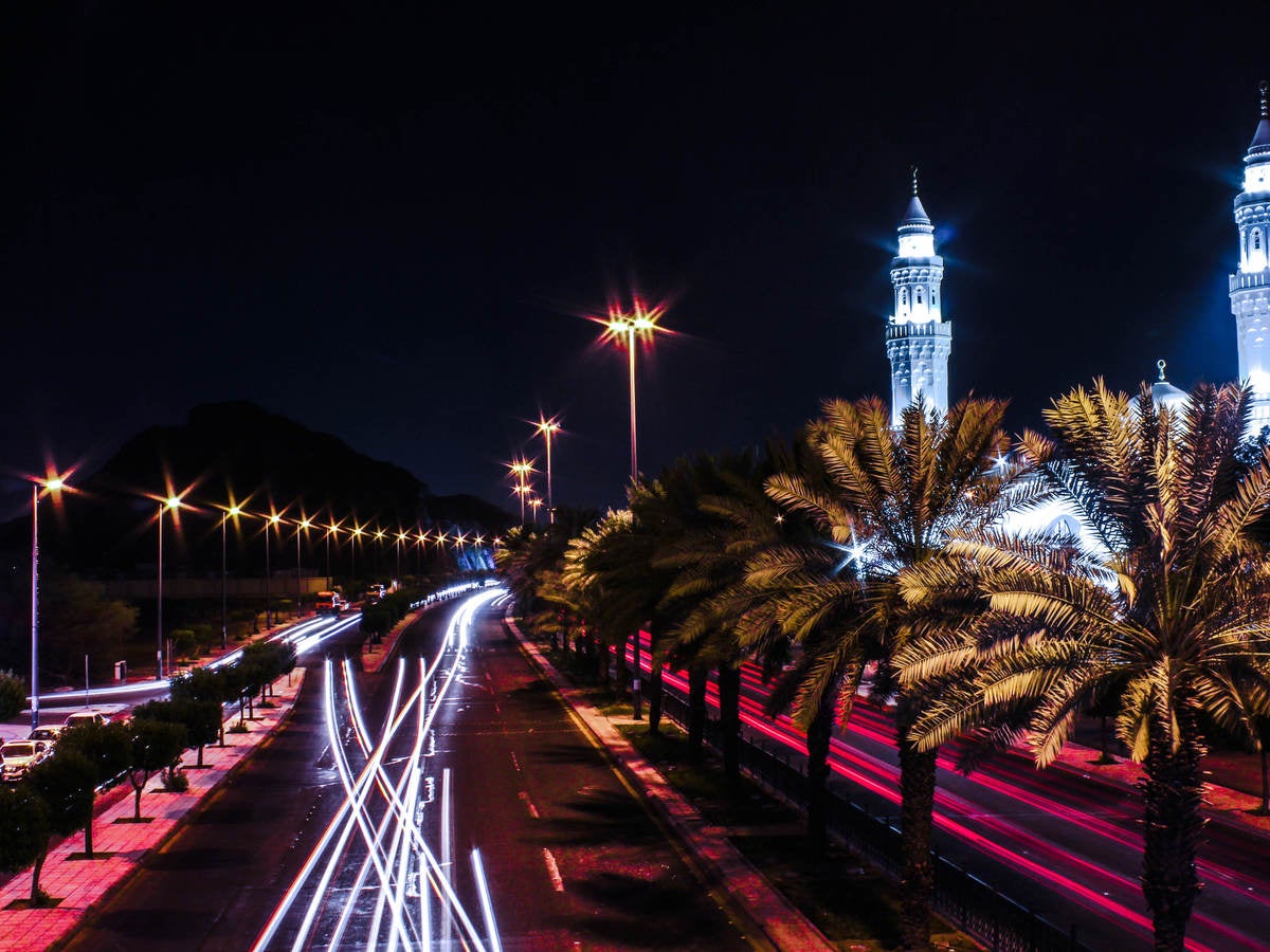 Street lights bordering busy street at night with palm trees