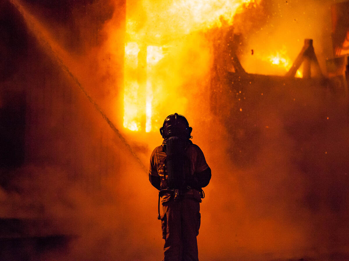 A firefighter sprays water on the outside of a burning building