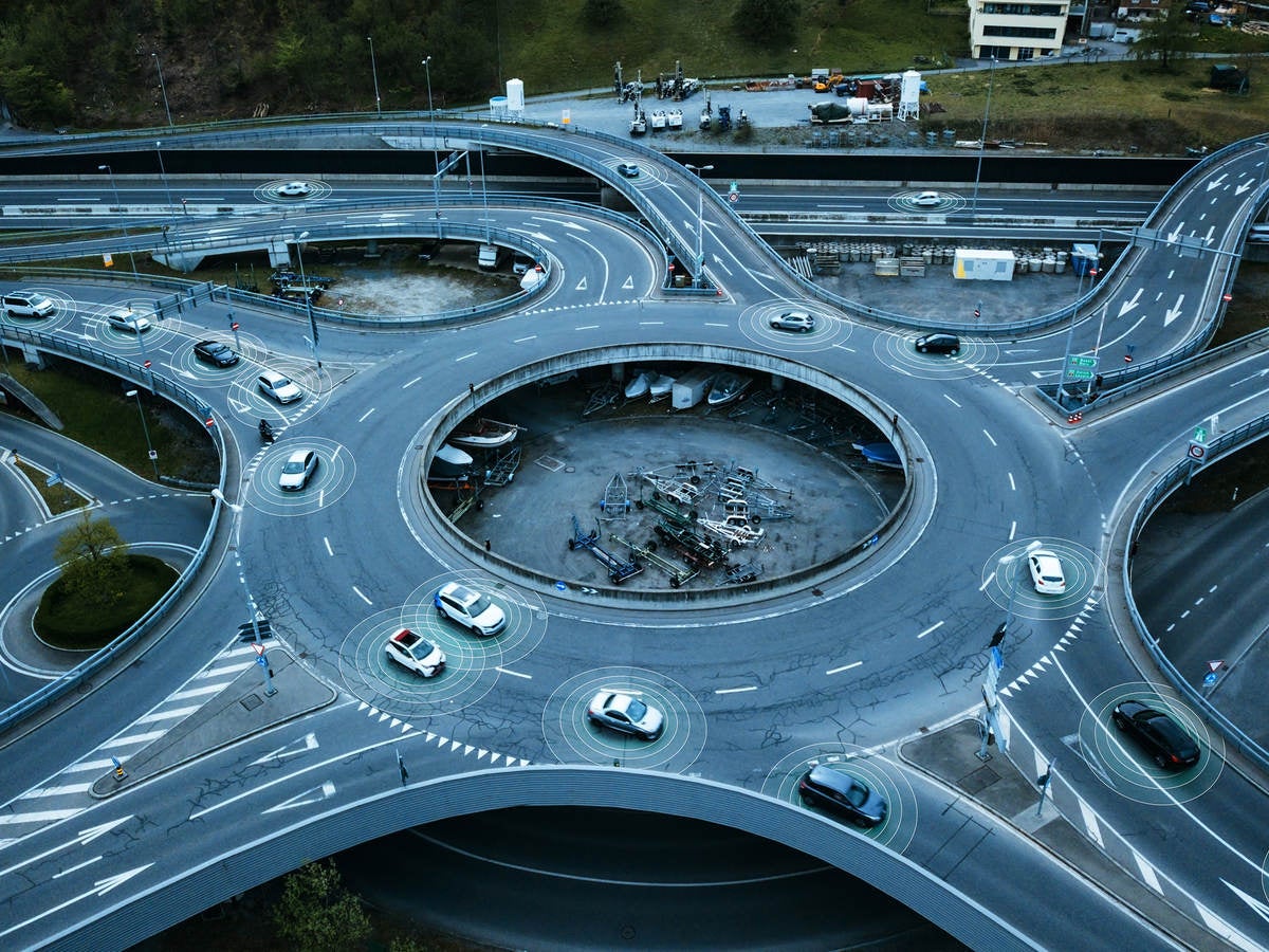 Autonomous self-driving cars moving in a traffic circle next to a highway. 