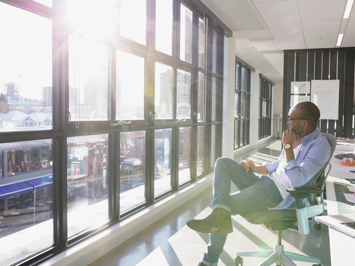 Pensive businessman looking out sunny office window