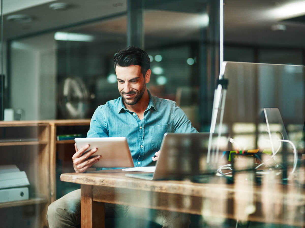 Smiling man looking at tablet in an office workspace