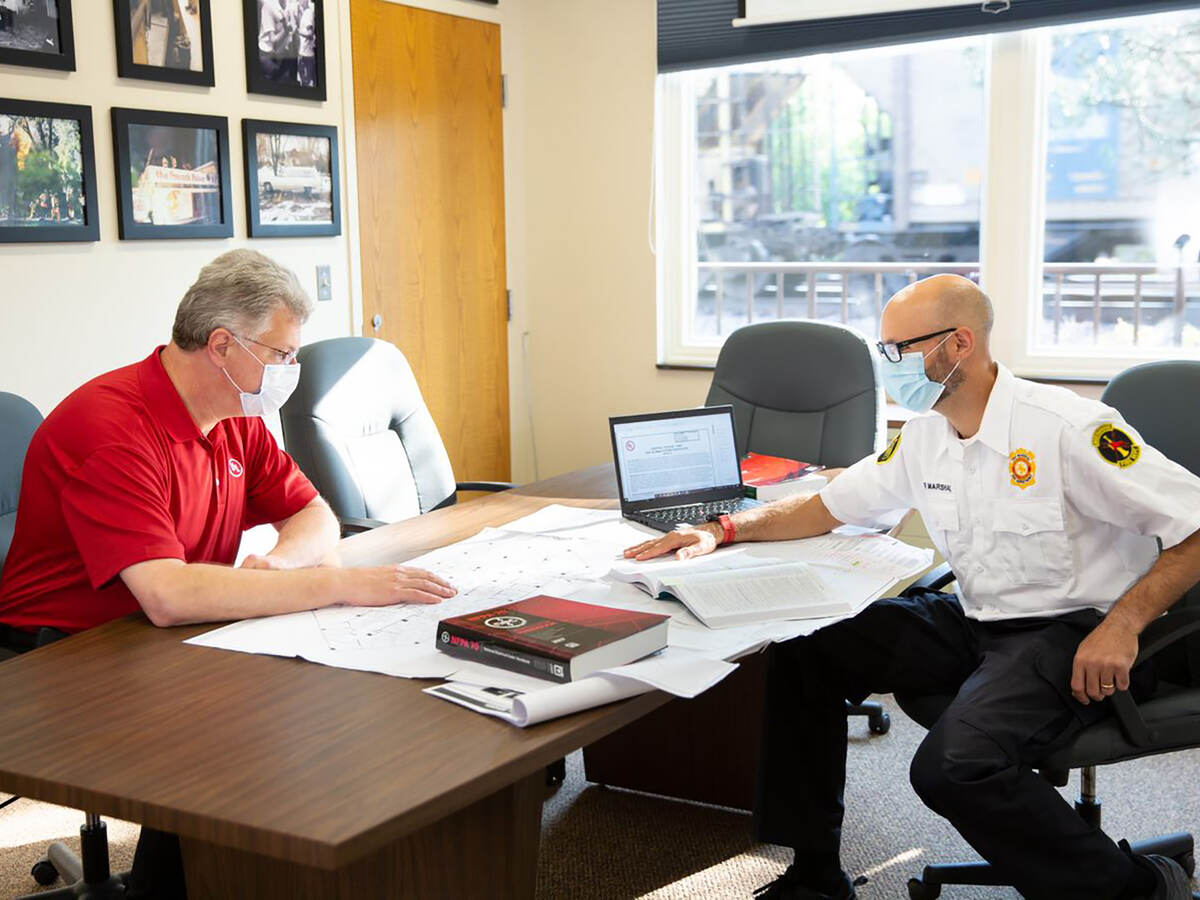 Two code authorities sitting at a table together looking at building plans.