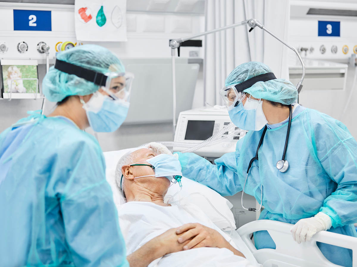 Medical professionals wearing personal protection equipment (PPE) attending to a hospital patient