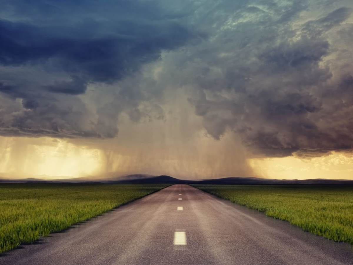 Road leading to a storm with clouds on the horizon.