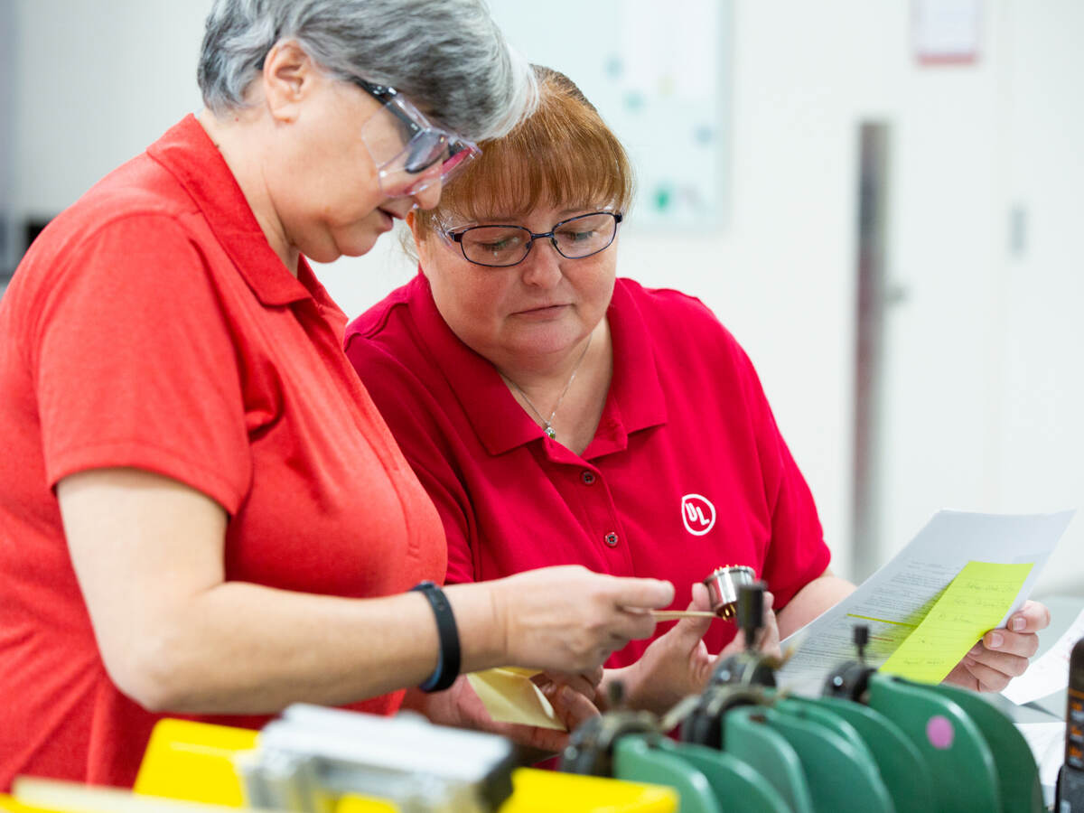 Two mature white female lab employees with safety glasses work together in the Materials Laboratory