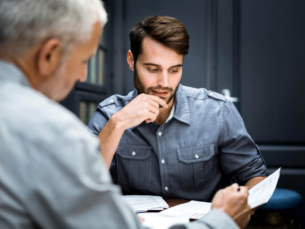 Two male business professionals reviewing documentation at workplace.