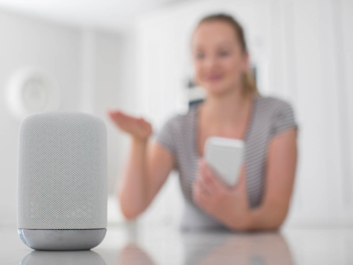 A woman uses wireless and interoperability services to operate a kitchen device with a smart phone.