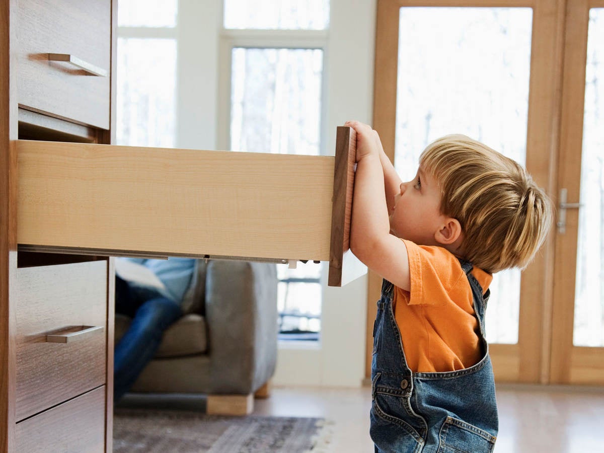 A child pulling on an open dresser drawer, a furniture tip-over risk