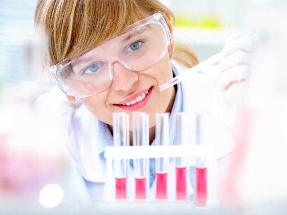 Female scientist dripping liquid into vials 