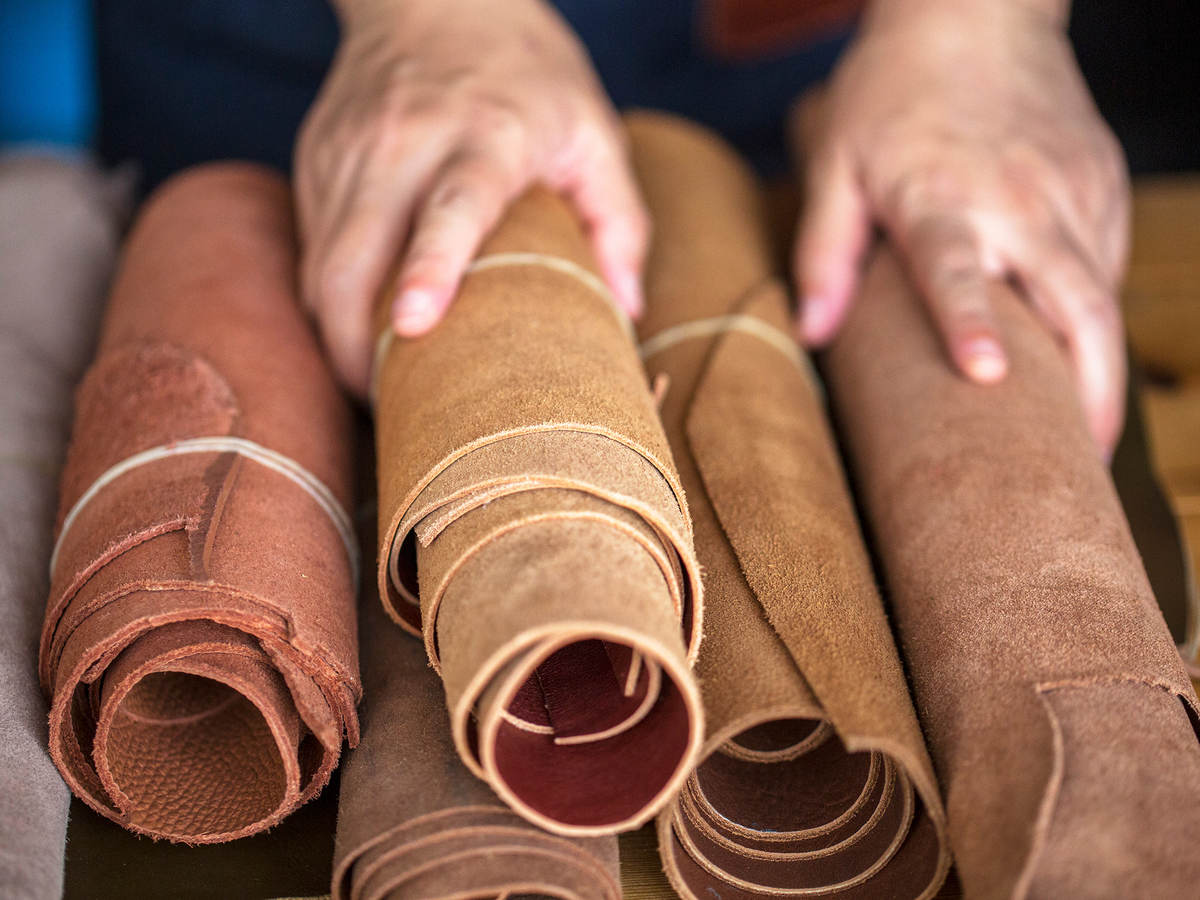 A pair of hands holds rolled leather sheets