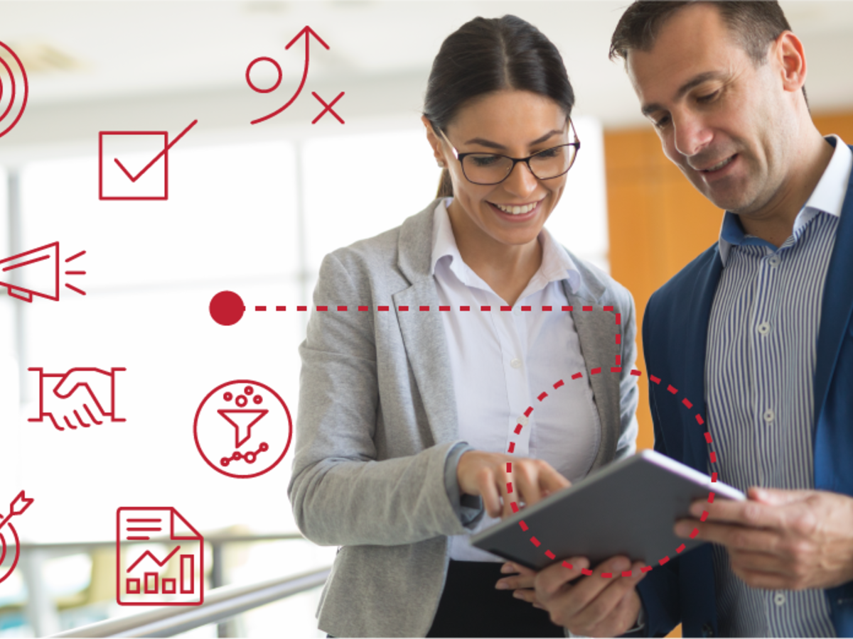 Two employees reviewing data on a tablet with icons around them