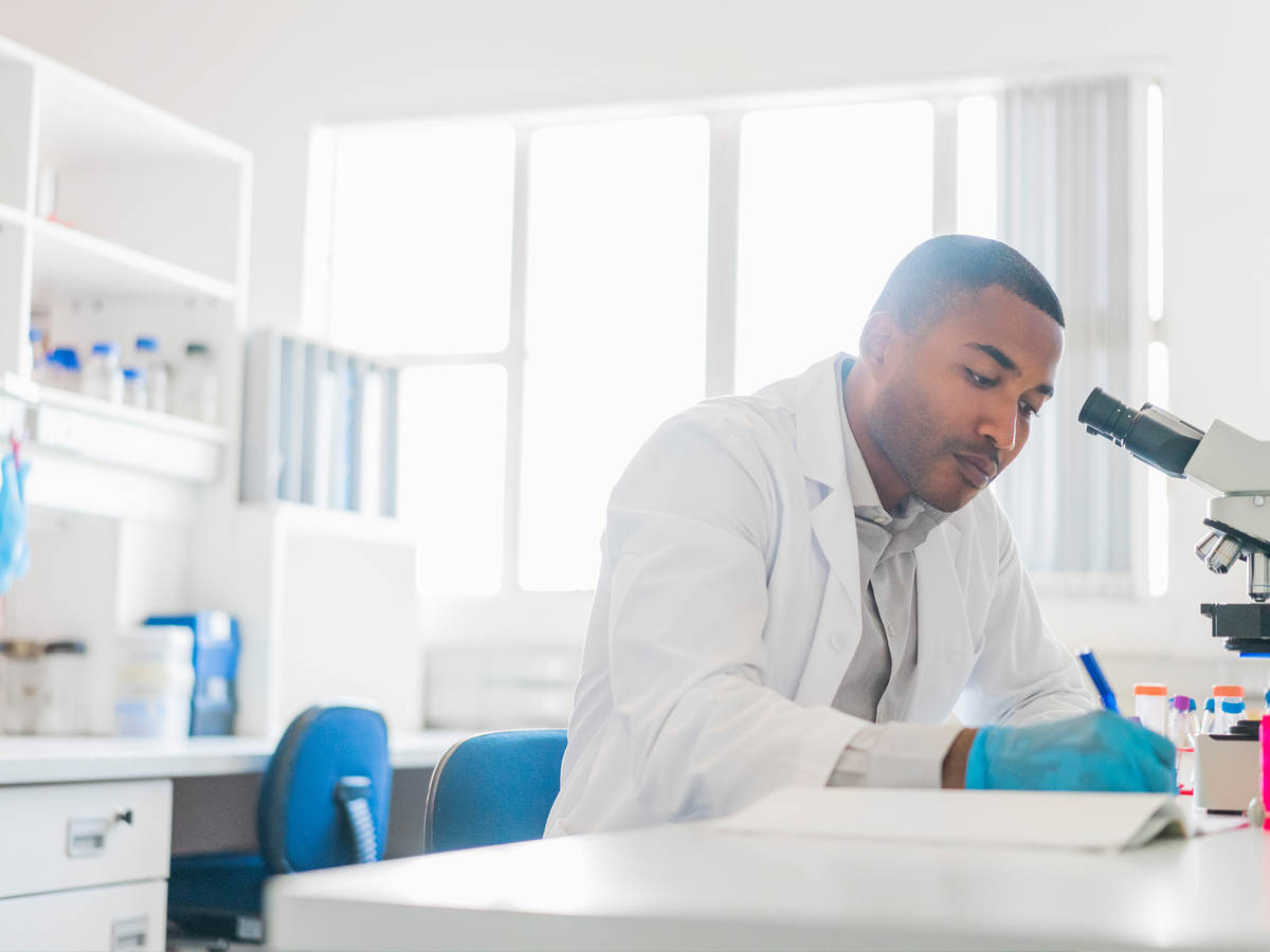 Chemist making reports by microscope at laboratory