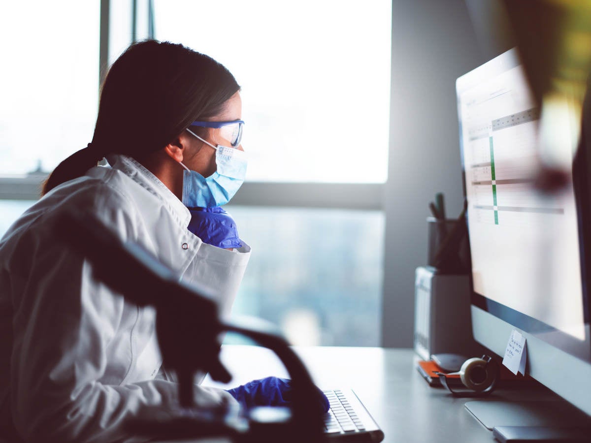 Female engineer with face mask at desk