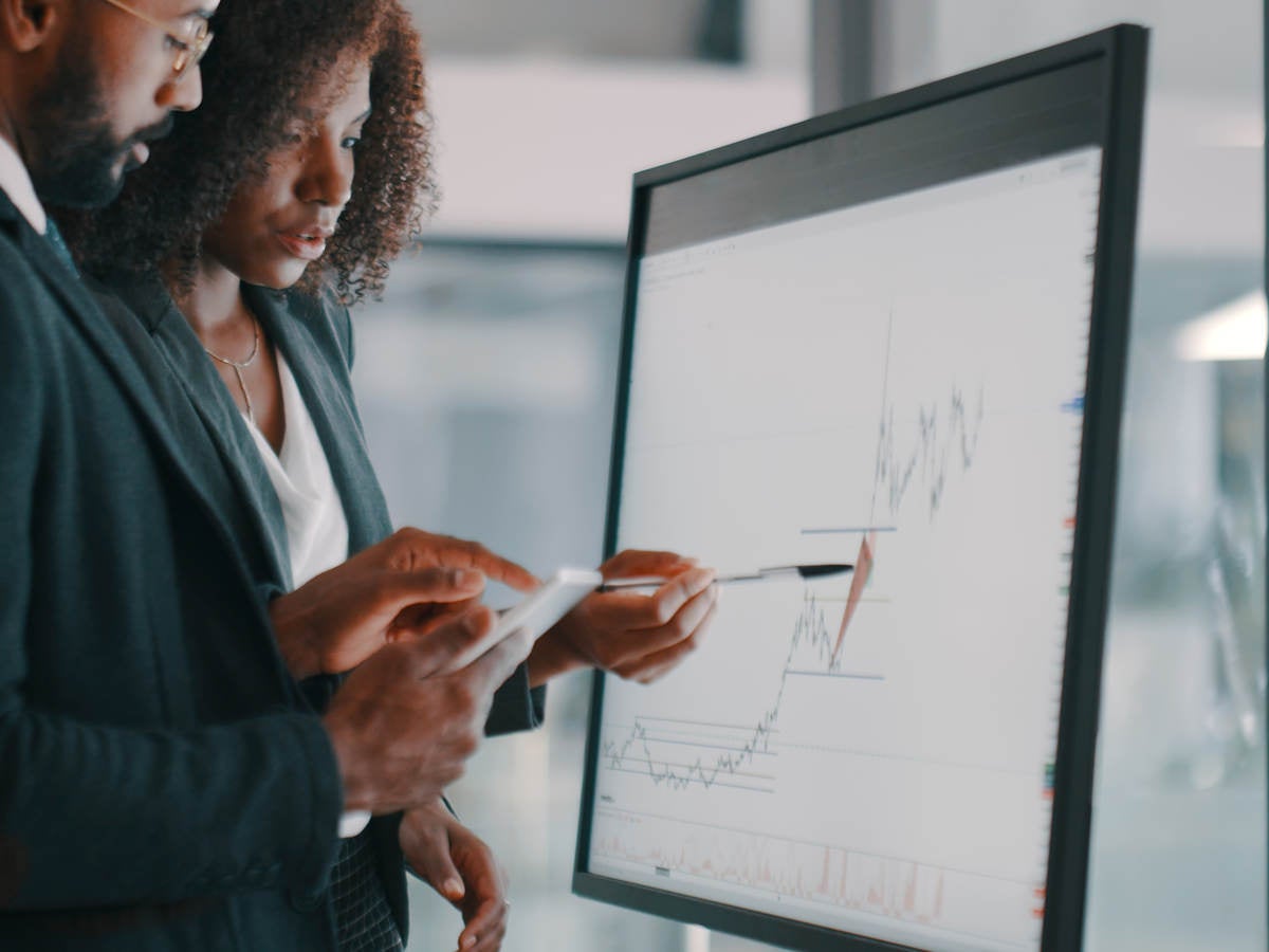 Shot of a young businessman and businesswoman using an interactive whiteboard to analyse data in a modern office