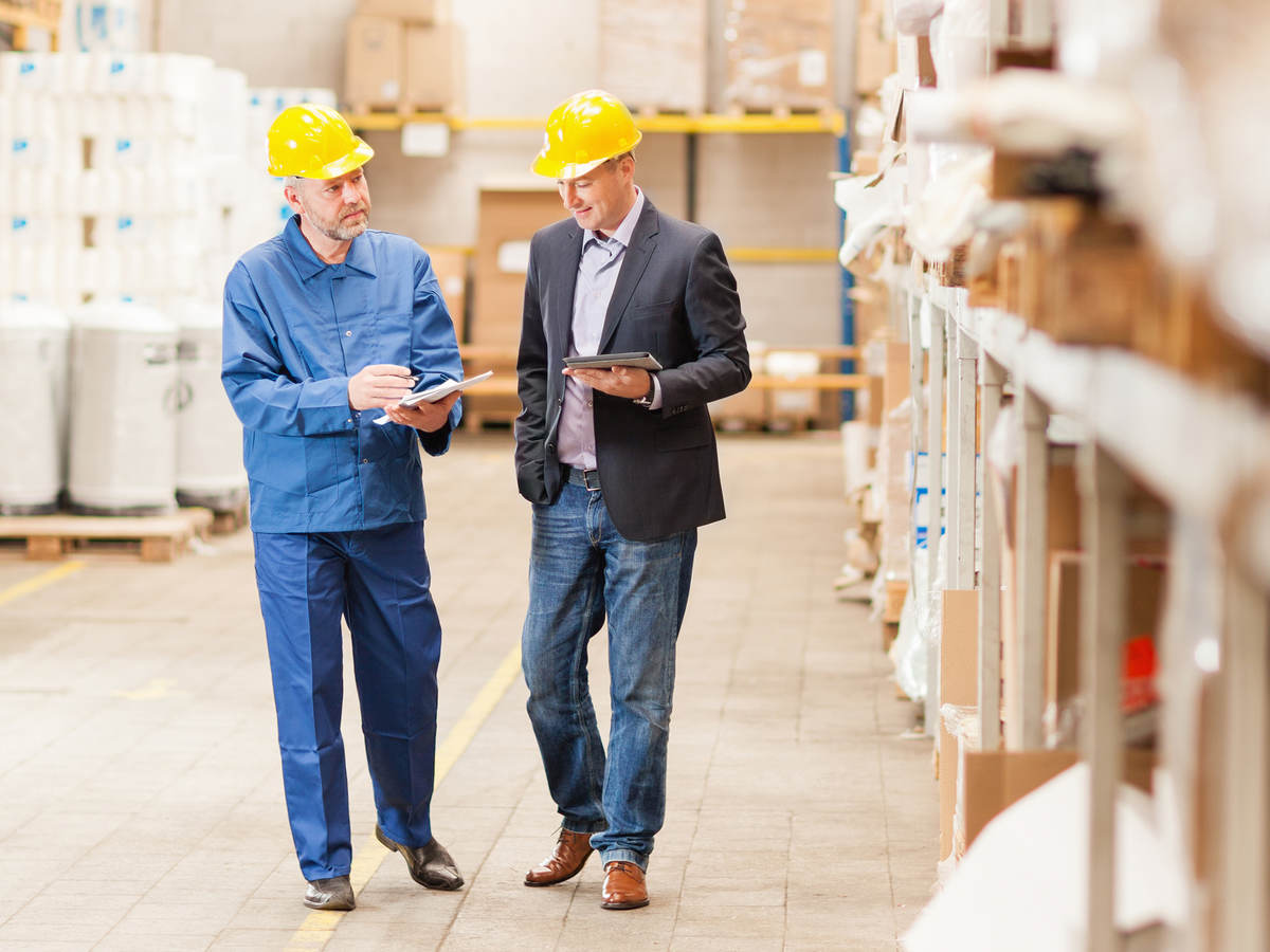 Men wearing hardhats in warehouse talking