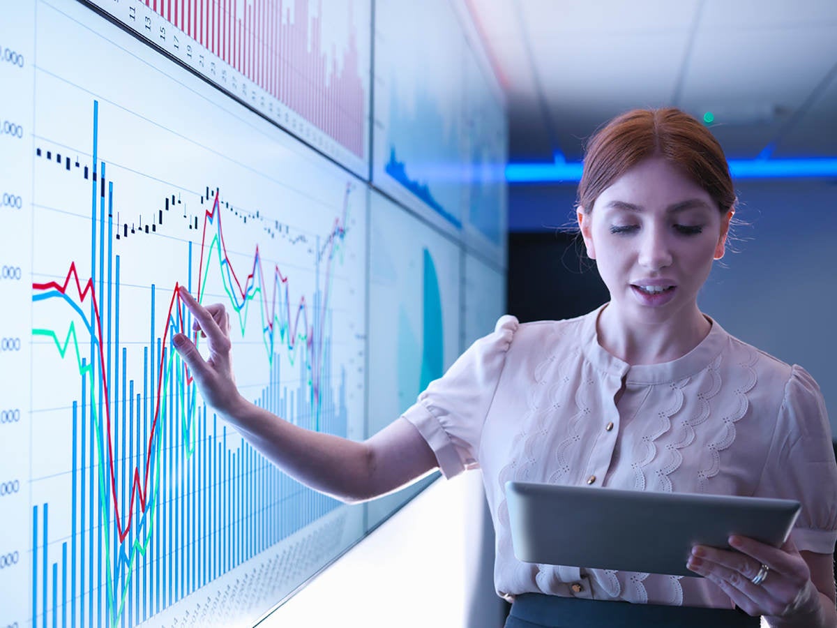 woman pointing to a chart on a whiteboard and using an ipad