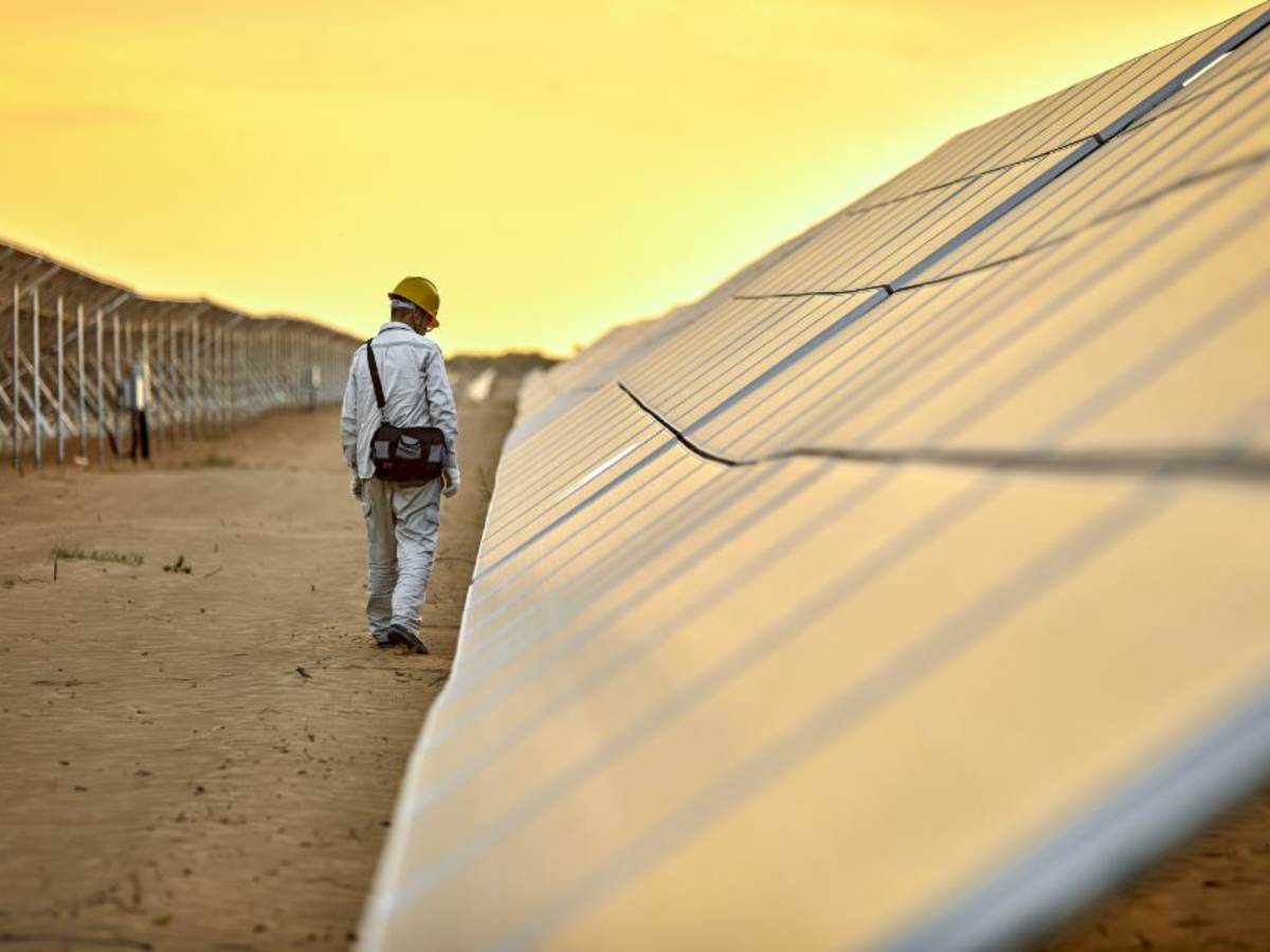Outdoor solar pnael test facility with golden sky  and with man inspecting PV solar panels