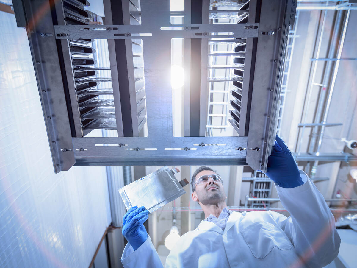 Scientist with lithium ion pouch cell manufacture machine in battery research facility