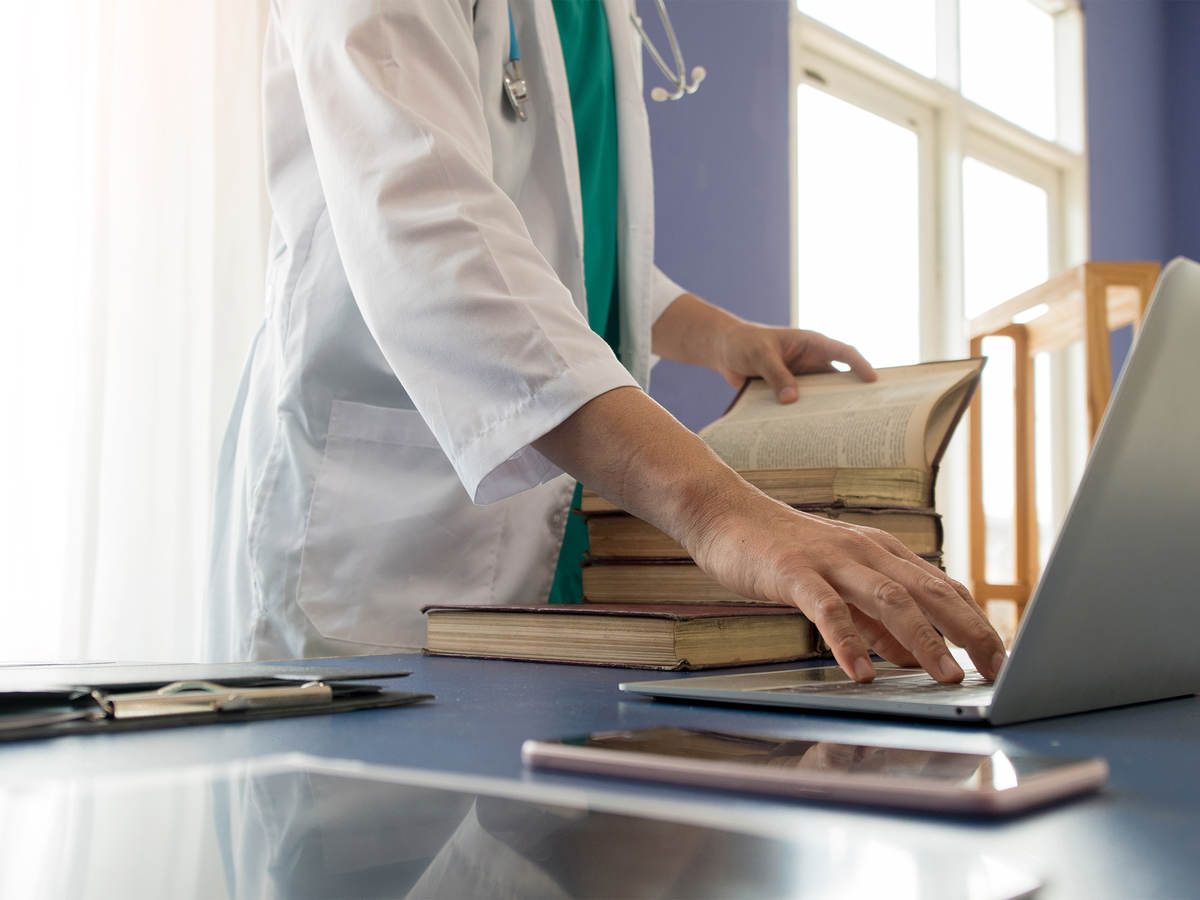 A medical professional’s hand, using laptop computer 