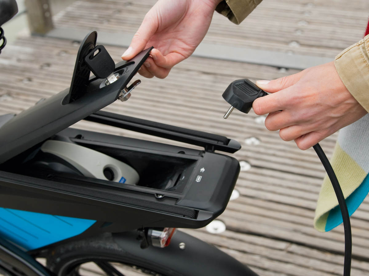 Woman charging electric bike outdoors