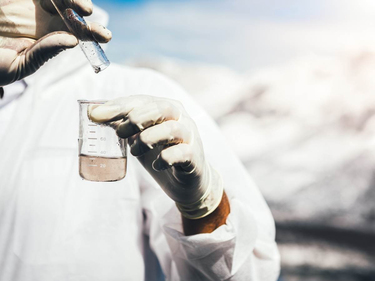 Person in protective suit examining polluted water