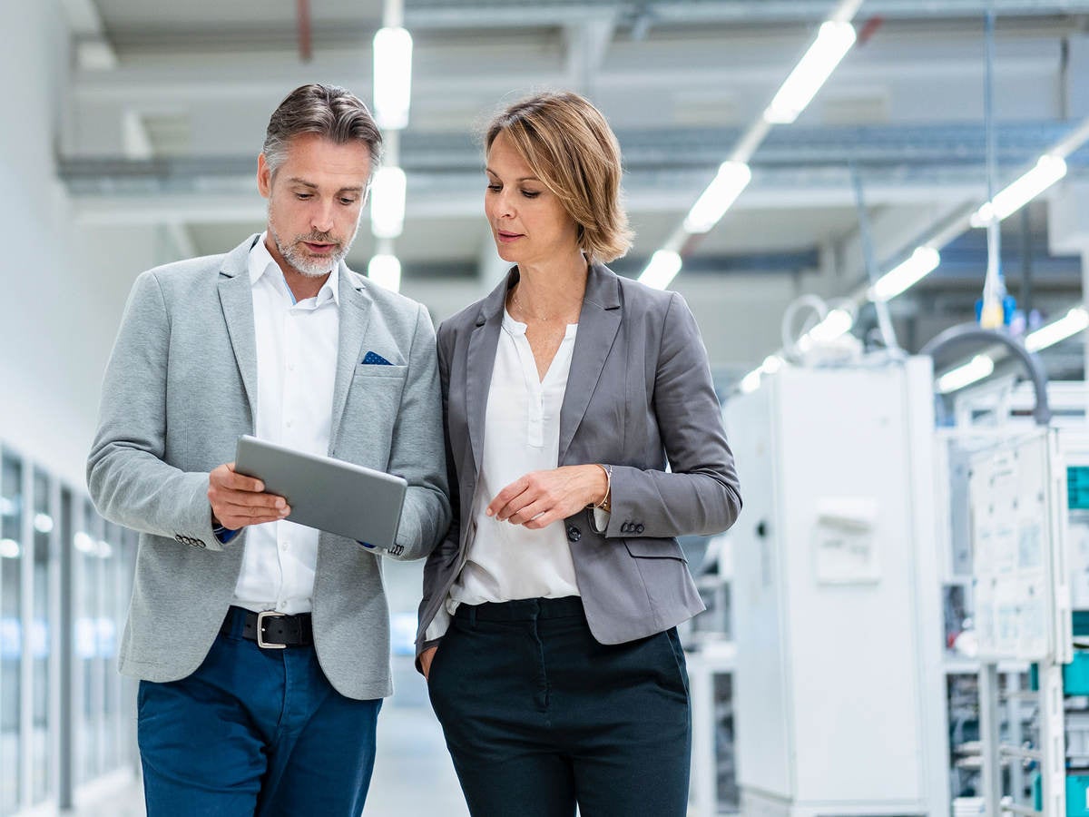 Two workers collaborating on a device while walking