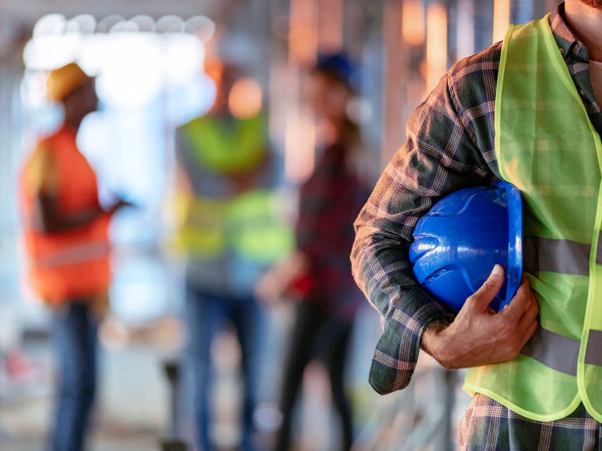 Man holding blue hard hat while on the job at warehouse