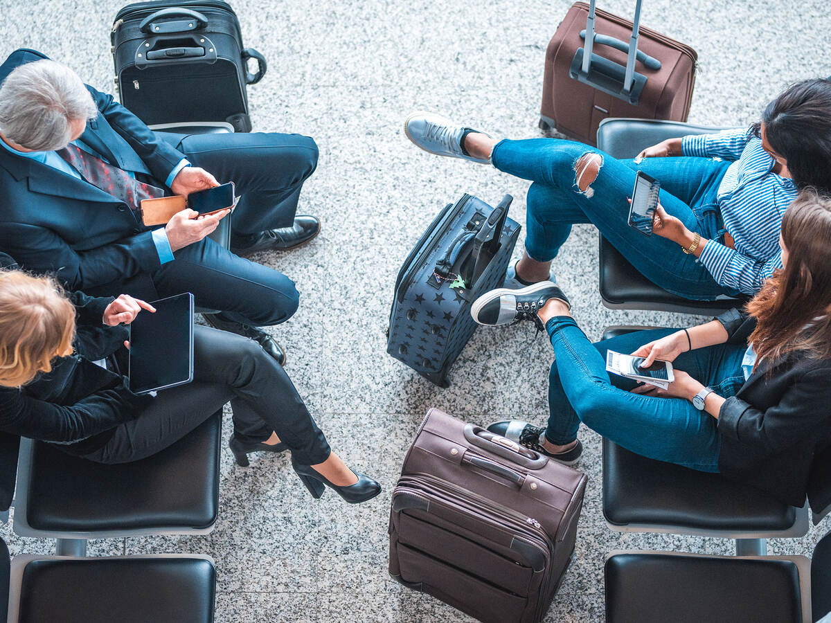 Passengers using mobile devices while waiting at an airport