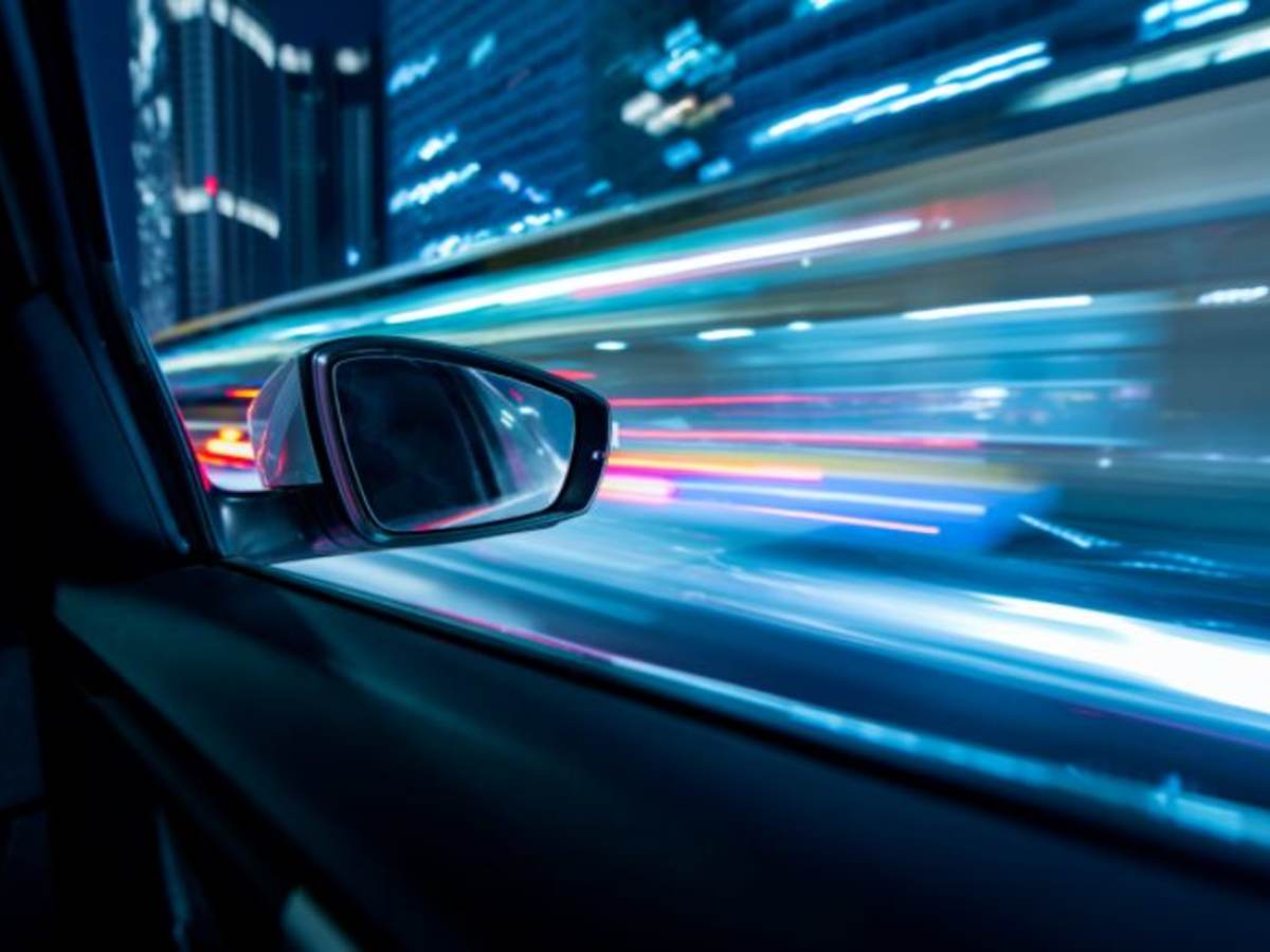 View from inside a moving car looking out of the passenger side with city lights in view