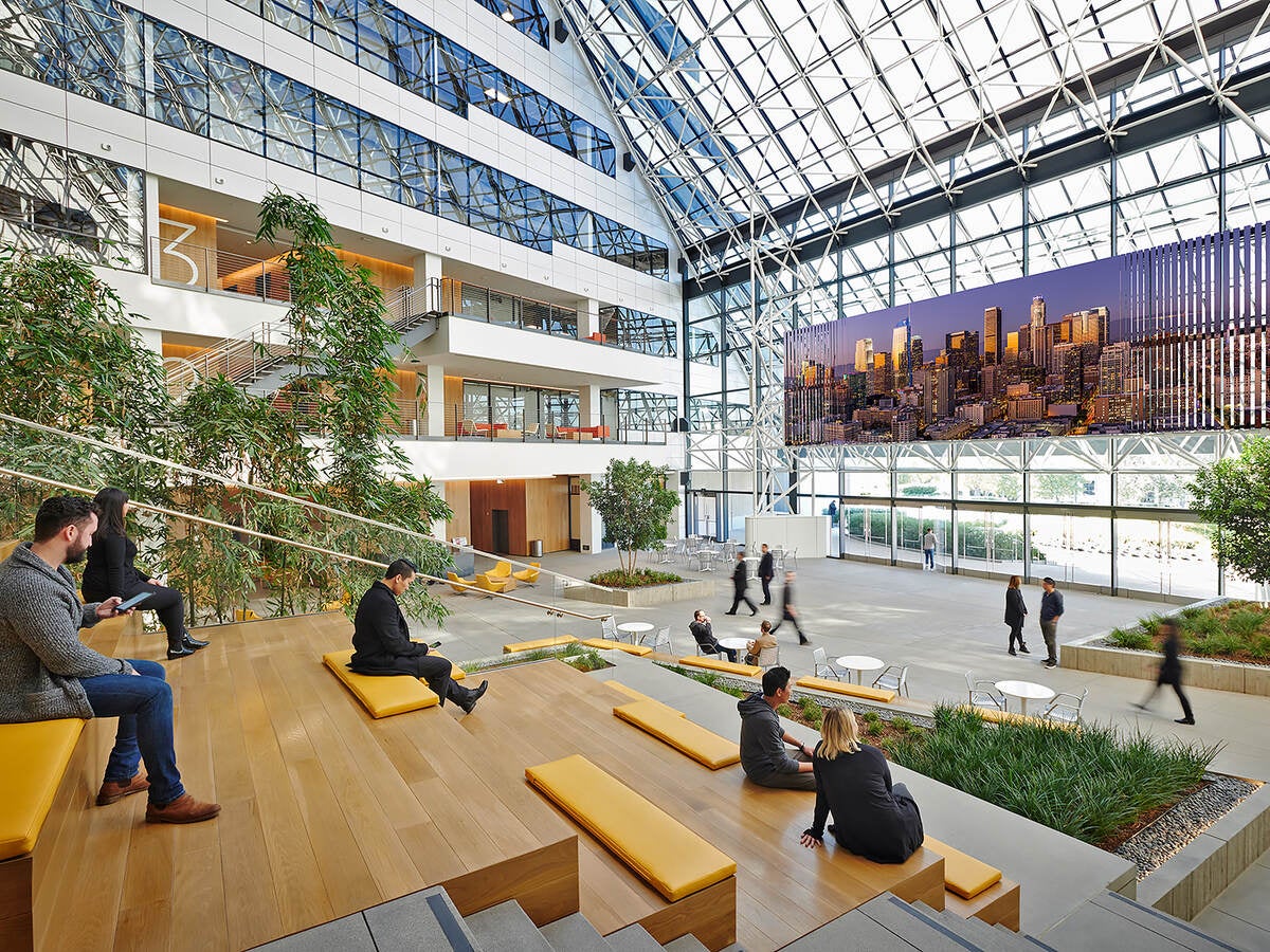 multi-storey atrium in commerical office building with people on wooden benches