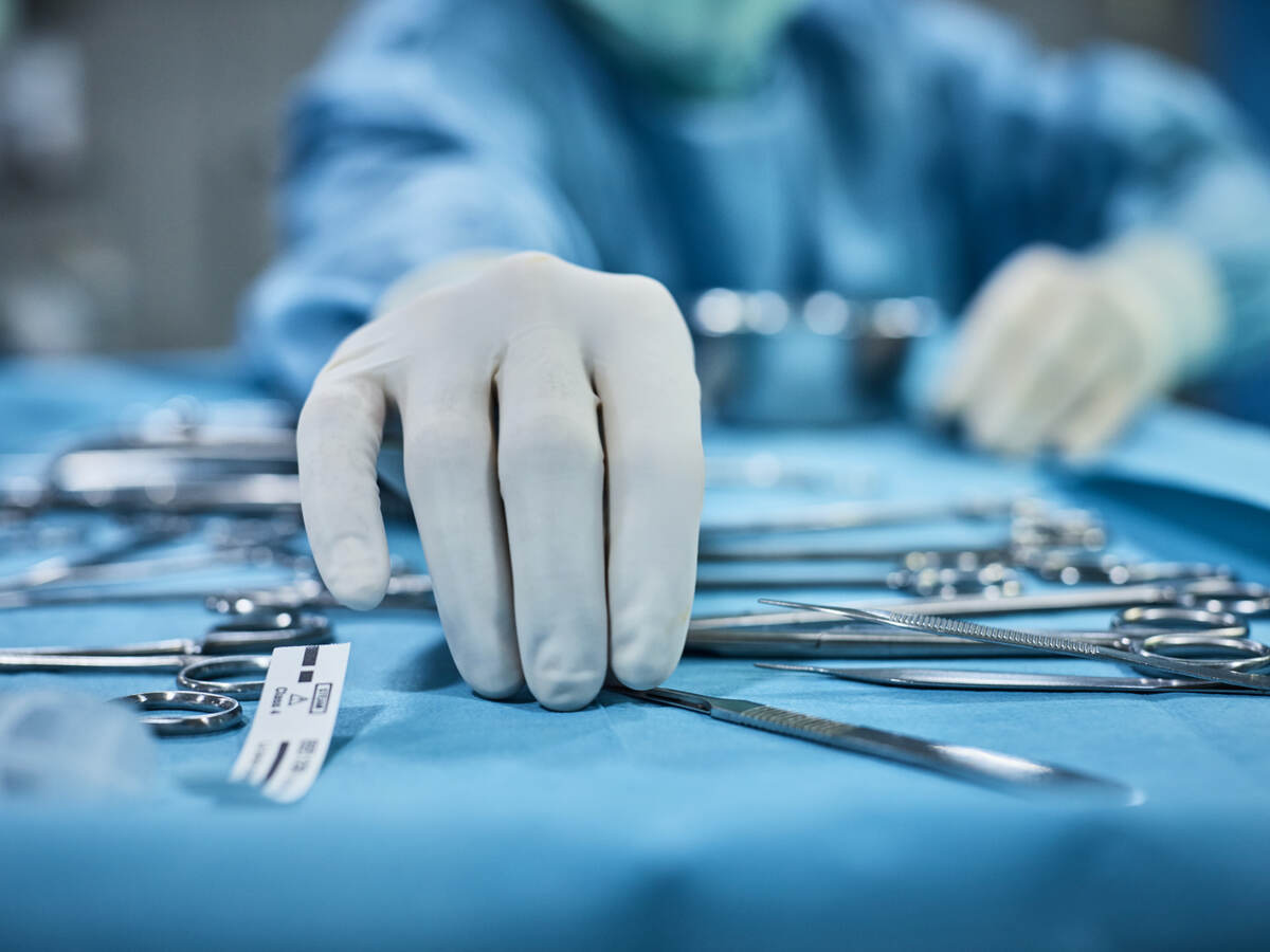 Surgeon picking up surgical tool from tray