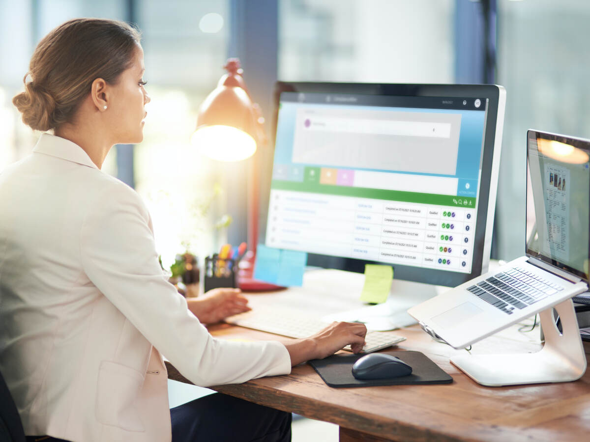 Woman sitting at desk in front of a computer monitor and laptop computer