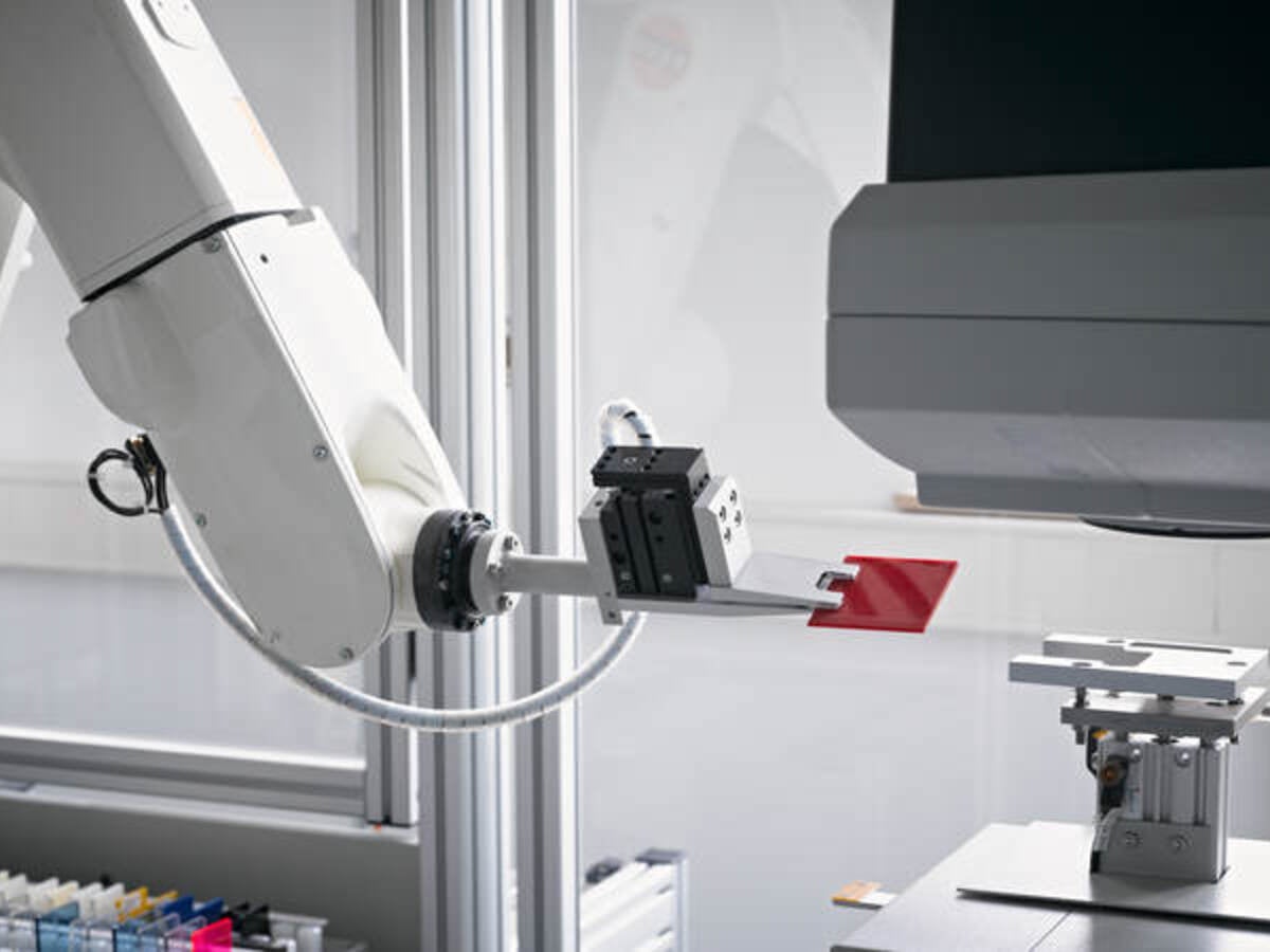 Mechanical arm holding red plastic sample piece