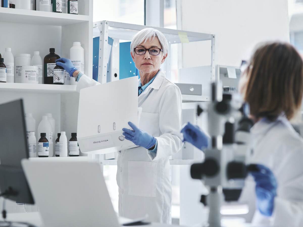 Gray-haired female scientist holding binder in lab