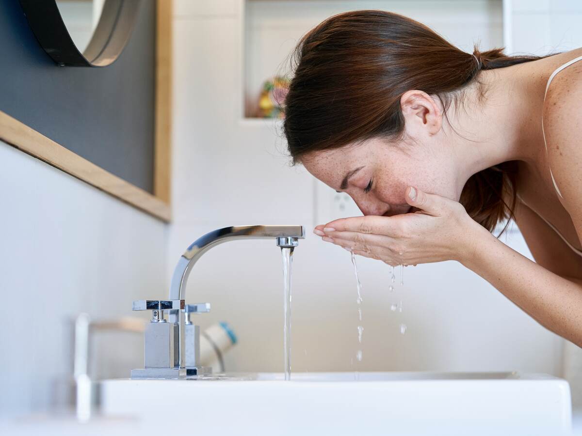 Person washing their face over a sink