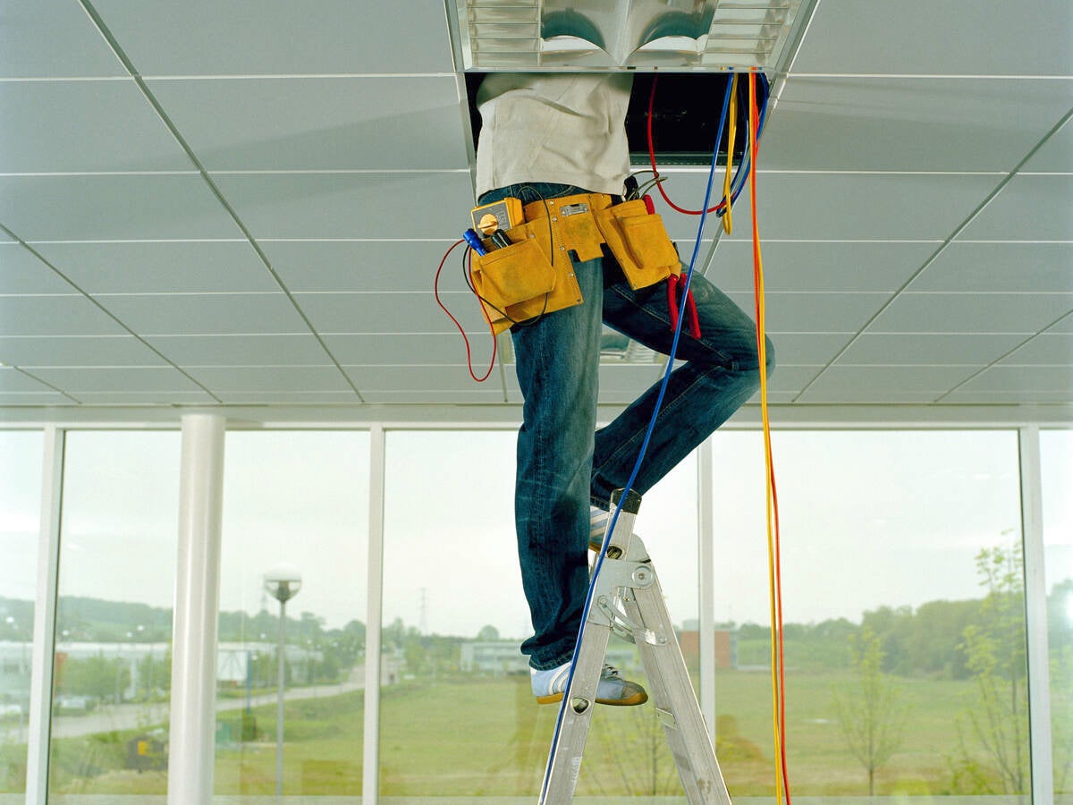 Man on step ladder, working through gap in ceiling, low section