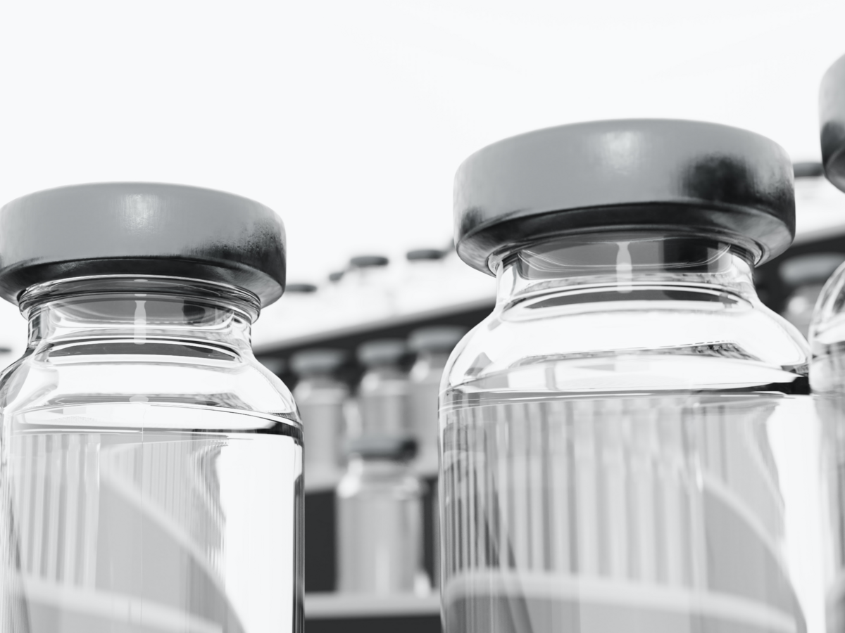 Low-angle photograph of vaccine vial in a freezer, surrounded by freezing fog