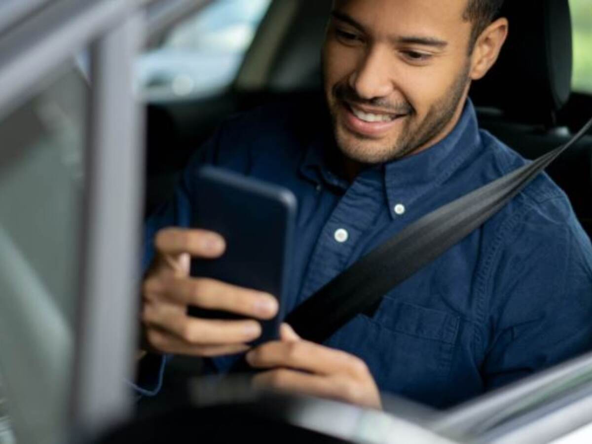 man sitting in car looking mobile driver license on smartphone